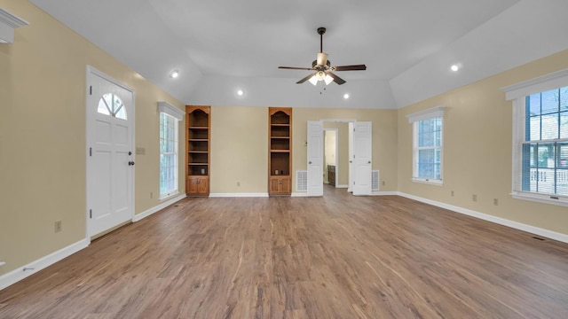 unfurnished living room with baseboards, built in features, vaulted ceiling, a ceiling fan, and wood finished floors