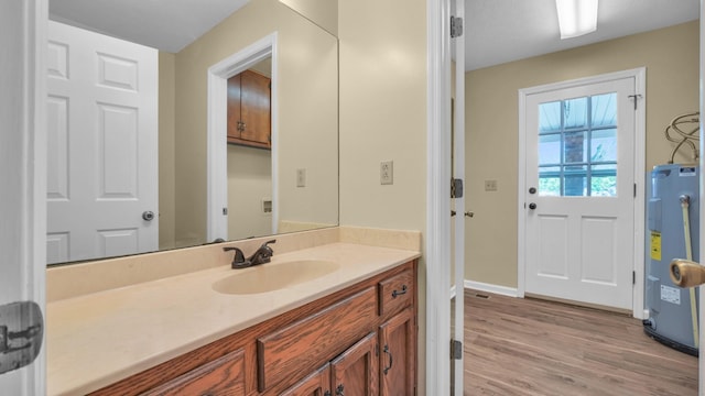 bathroom with wood finished floors, vanity, baseboards, and water heater