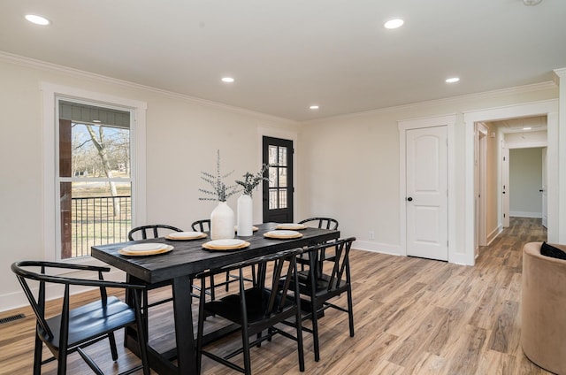 dining area with light wood finished floors, visible vents, baseboards, and crown molding