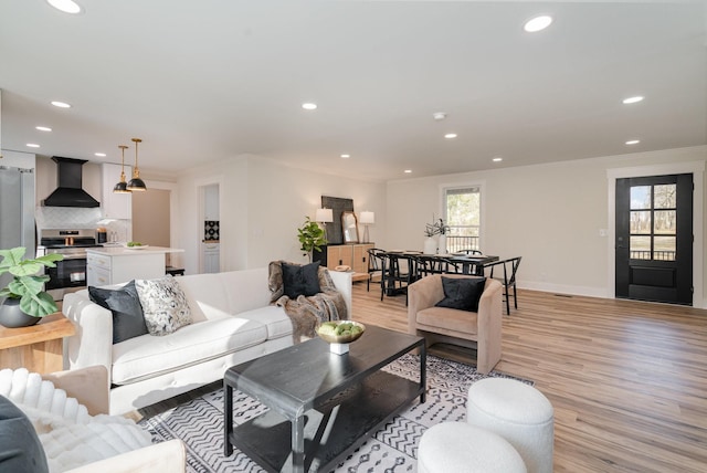 living area featuring light wood-style floors, baseboards, ornamental molding, and recessed lighting