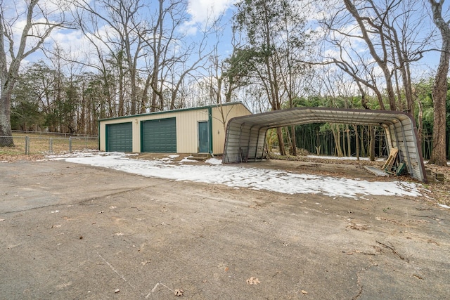 detached garage with a carport and fence