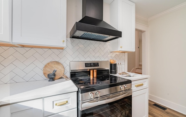 kitchen with ornamental molding, wall chimney range hood, white cabinetry, visible vents, and stainless steel electric stove