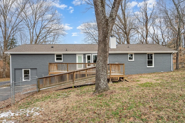 rear view of house featuring a yard, fence, brick siding, a chimney, and a deck