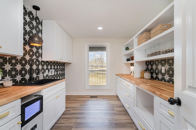 kitchen featuring backsplash, open shelves, butcher block counters, white cabinets, and a sink