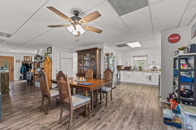 dining space featuring visible vents, light wood-style flooring, a ceiling fan, and a drop ceiling