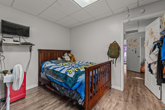 bedroom featuring a paneled ceiling, wood finished floors, and baseboards