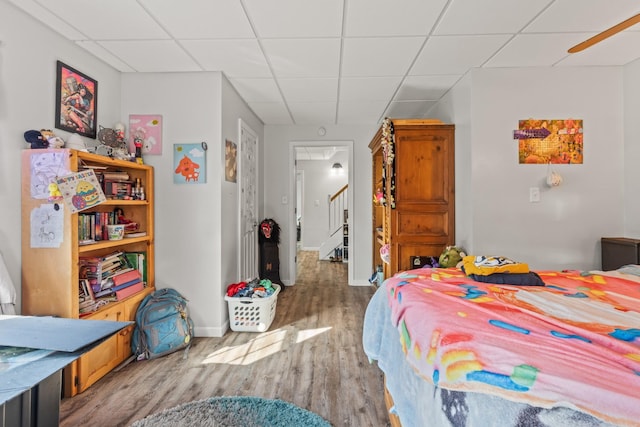 bedroom featuring a paneled ceiling, wood finished floors, and baseboards