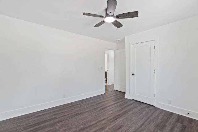 empty room featuring dark wood-type flooring, baseboards, and a ceiling fan
