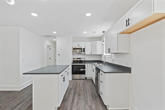 kitchen featuring visible vents, appliances with stainless steel finishes, a sink, dark countertops, and dark wood-style floors
