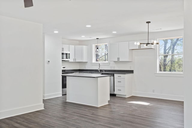 kitchen with baseboards, appliances with stainless steel finishes, dark countertops, and white cabinets