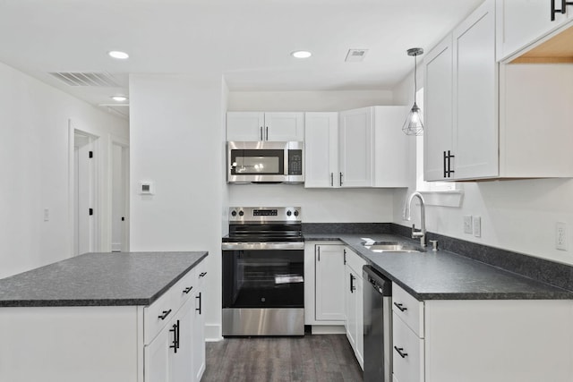 kitchen with dark countertops, visible vents, appliances with stainless steel finishes, and a sink