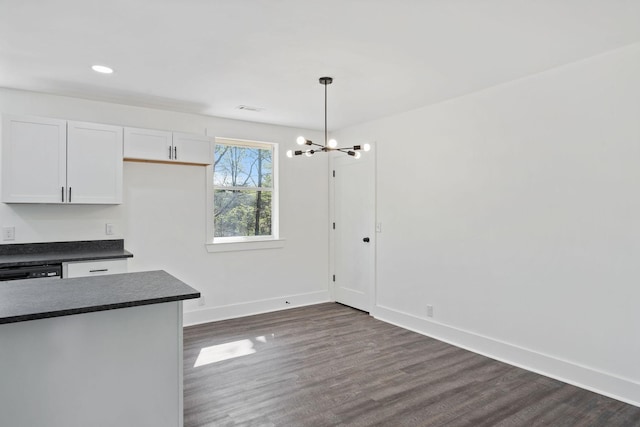 kitchen with baseboards, white cabinets, dark wood-style flooring, dark countertops, and a chandelier