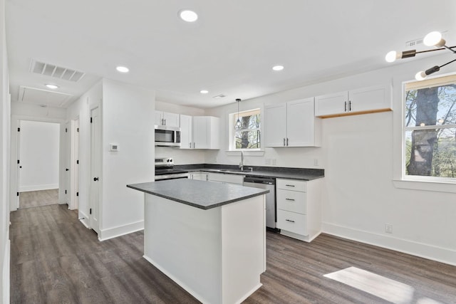 kitchen with visible vents, white cabinets, a sink, dark countertops, and stainless steel appliances
