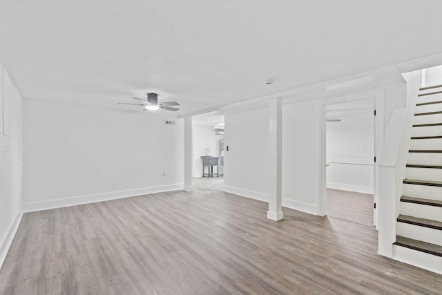 unfurnished living room featuring baseboards, stairway, a ceiling fan, visible vents, and wood finished floors