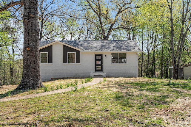 single story home featuring brick siding, a front lawn, and a shingled roof