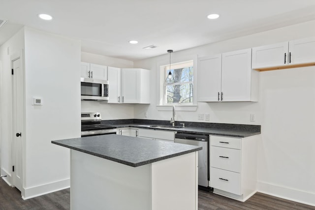 kitchen with baseboards, dark countertops, dark wood finished floors, stainless steel appliances, and a sink
