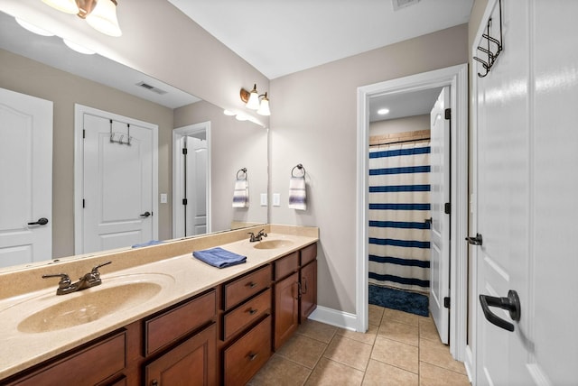 bathroom with a sink, baseboards, double vanity, and tile patterned flooring