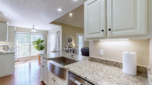 kitchen with light stone counters, white cabinetry, dishwasher, a sink, and wood finished floors