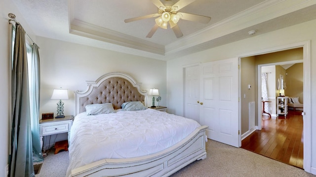 carpeted bedroom featuring baseboards, a tray ceiling, ornamental molding, and ceiling fan