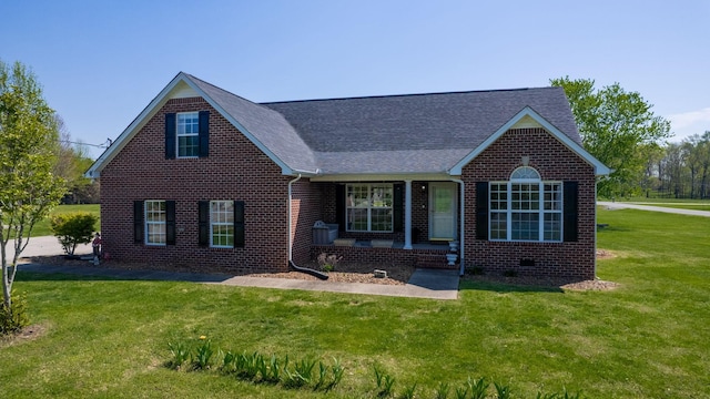 view of front of house with a shingled roof, a front yard, and brick siding