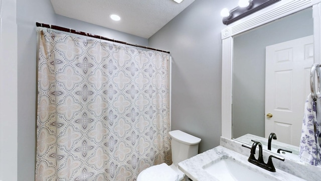 full bath featuring curtained shower, vanity, a textured ceiling, and toilet