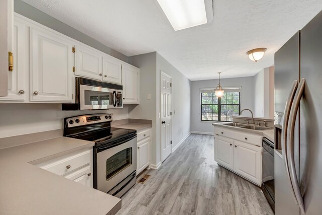 308 Wareham Ct, Antioch, TN 37013 - kitchen with white cabinetry, appliances with stainless steel finishes, light countertops, a sink, and light wood finished floors
