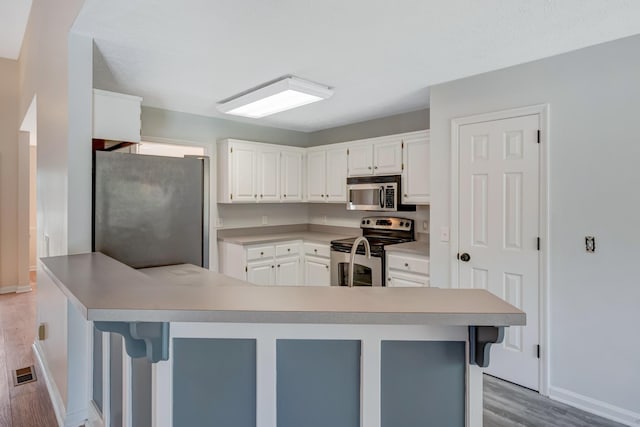 308 Wareham Ct, Antioch, TN 37013 - kitchen with baseboards, light wood-style flooring, white cabinetry, visible vents, and stainless steel appliances