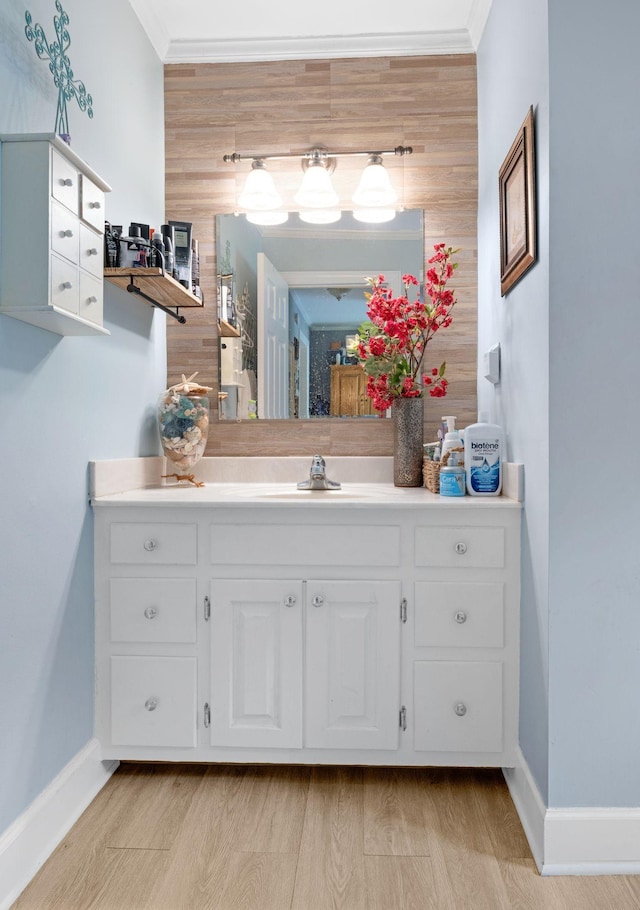 bathroom featuring crown molding, wood finished floors, vanity, and baseboards