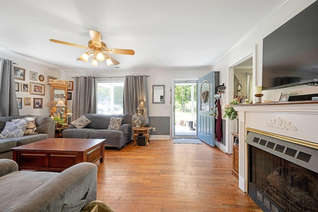 living room featuring light wood-type flooring, a fireplace, crown molding, and a wealth of natural light