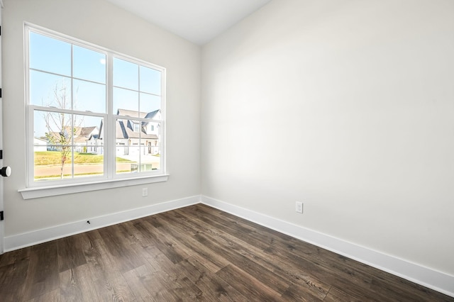 unfurnished room with baseboards, a wealth of natural light, and dark wood-style floors