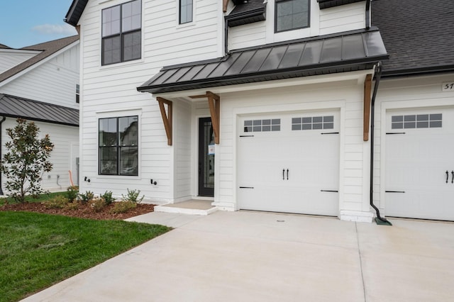 view of front of property with a shingled roof, a garage, a standing seam roof, driveway, and metal roof