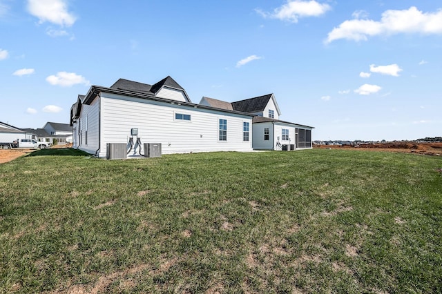 back of property with central AC and a yard