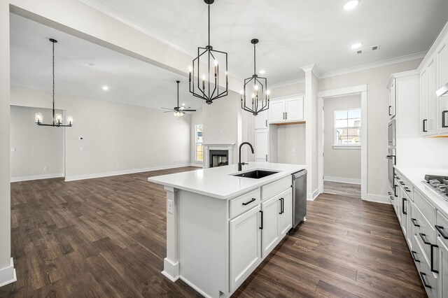 kitchen with appliances with stainless steel finishes, a sink, a fireplace, ceiling fan with notable chandelier, and visible vents