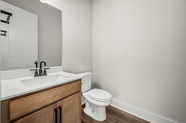 bathroom featuring vanity, baseboards, wood finished floors, and toilet