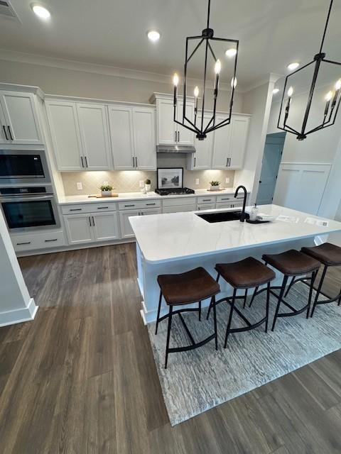5739 Sagebrush Dr, Murfreesboro, TN 37129 - kitchen with stainless steel appliances, a chandelier, crown molding, white cabinets, and dark wood-style floors