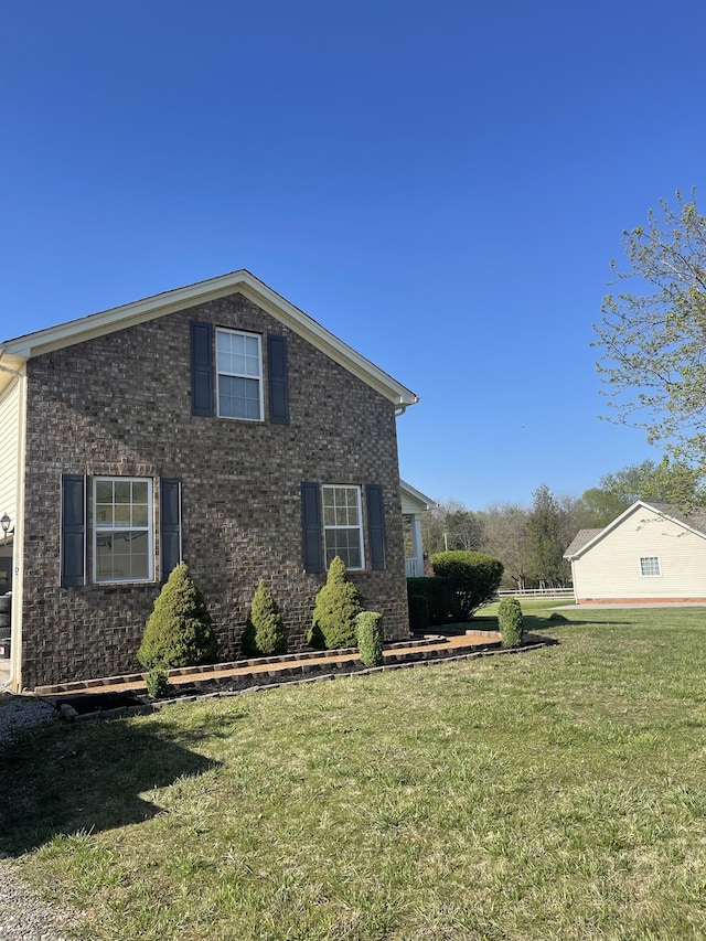 view of home's exterior with brick siding and a lawn