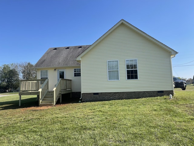 rear view of property featuring a yard, a deck, crawl space, and roof with shingles