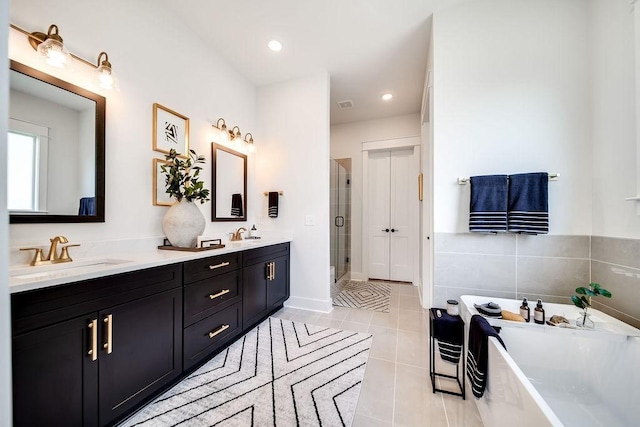 full bathroom featuring double vanity, a freestanding tub, a stall shower, a sink, and tile patterned floors