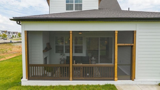 rear view of property featuring a sunroom and roof with shingles