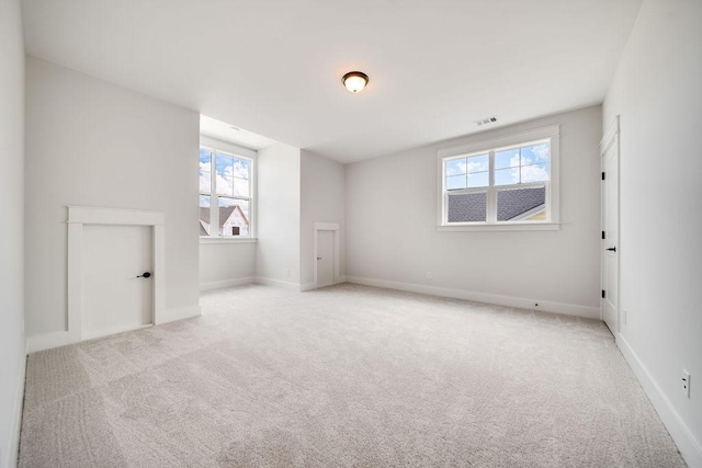 spare room featuring baseboards, visible vents, plenty of natural light, and carpet