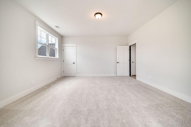 unfurnished room featuring visible vents, baseboards, and light colored carpet