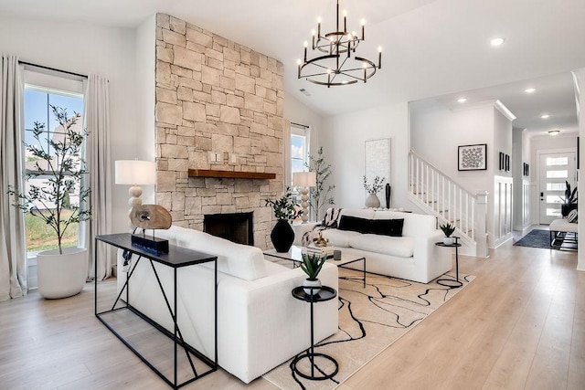 living area featuring stairway, a notable chandelier, light wood-style flooring, and a wealth of natural light