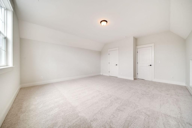 bonus room featuring baseboards, light carpet, and lofted ceiling