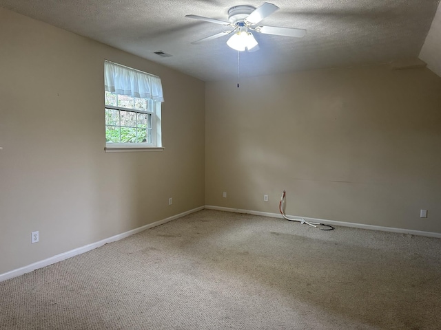 carpeted spare room with a ceiling fan, a textured ceiling, and baseboards
