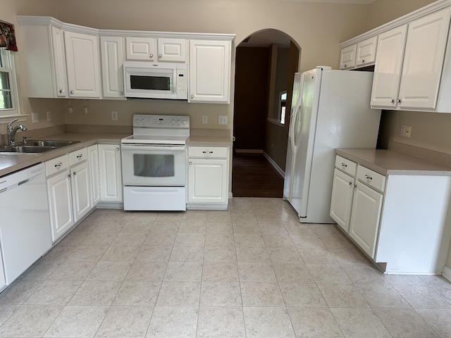 kitchen featuring white appliances, a sink, arched walkways, and white cabinetry