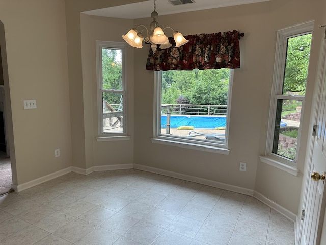 unfurnished dining area featuring healthy amount of natural light, a chandelier, and baseboards