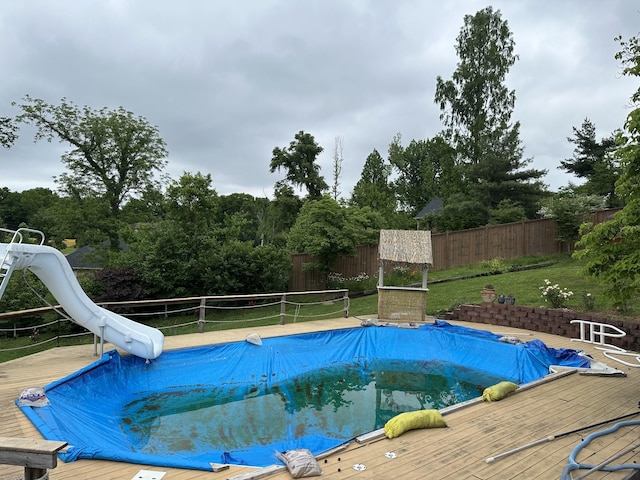 view of swimming pool featuring a water slide and a wooden deck