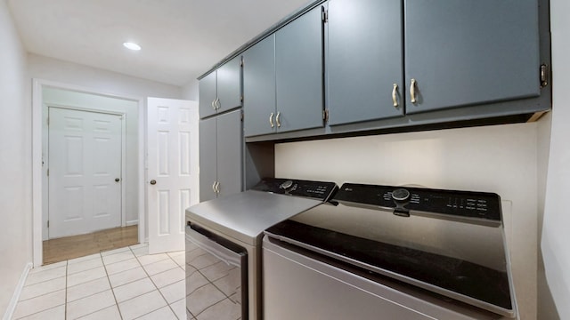 clothes washing area with separate washer and dryer, light tile patterned floors, baseboards, and cabinet space