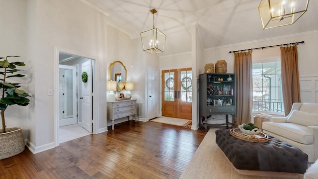foyer entrance featuring a wealth of natural light, high vaulted ceiling, an inviting chandelier, and wood finished floors