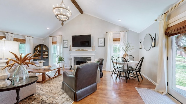 living room featuring light wood-style floors, an inviting chandelier, vaulted ceiling with beams, a tile fireplace, and baseboards